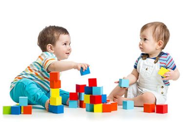 Deux enfants jouent avec des blocs de couleur