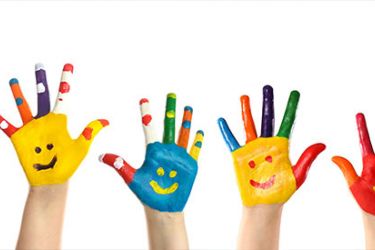 Photographie de mains d'enfants avec des visages fait avec de la peinture