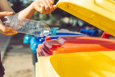 Personne jetant sa bouteille en plastique dans la poubelle jaune