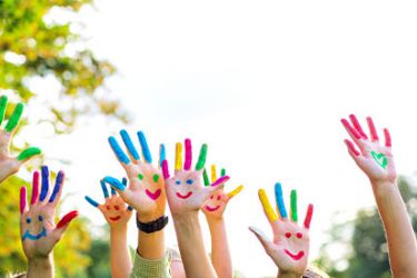 Photographie de mains d'enfants avec des visages fait avec de la peinture